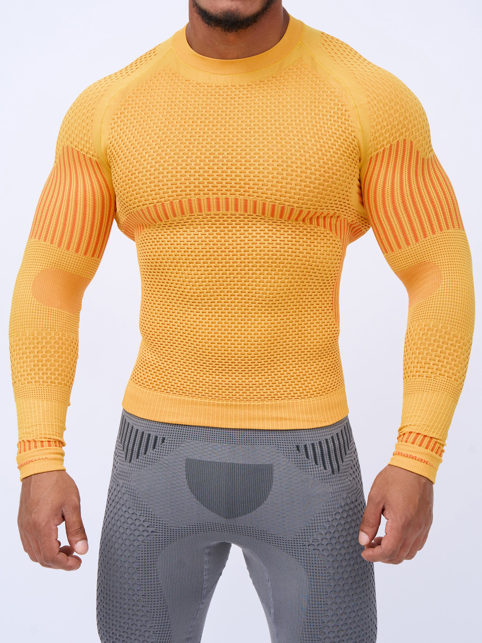 UltramaxCell men's orange seamless long-sleeve top with grey ankle-length leggings, close-up front view